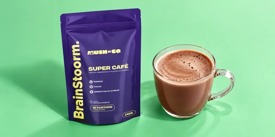 Busta di Brainstoorm di Mush N Go con una tazza di vetro piena di bevanda calda al cacao su fondo verde menta